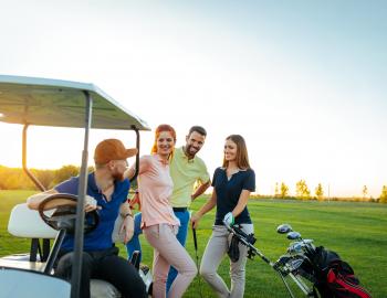 Group of people on golf course with golf cart